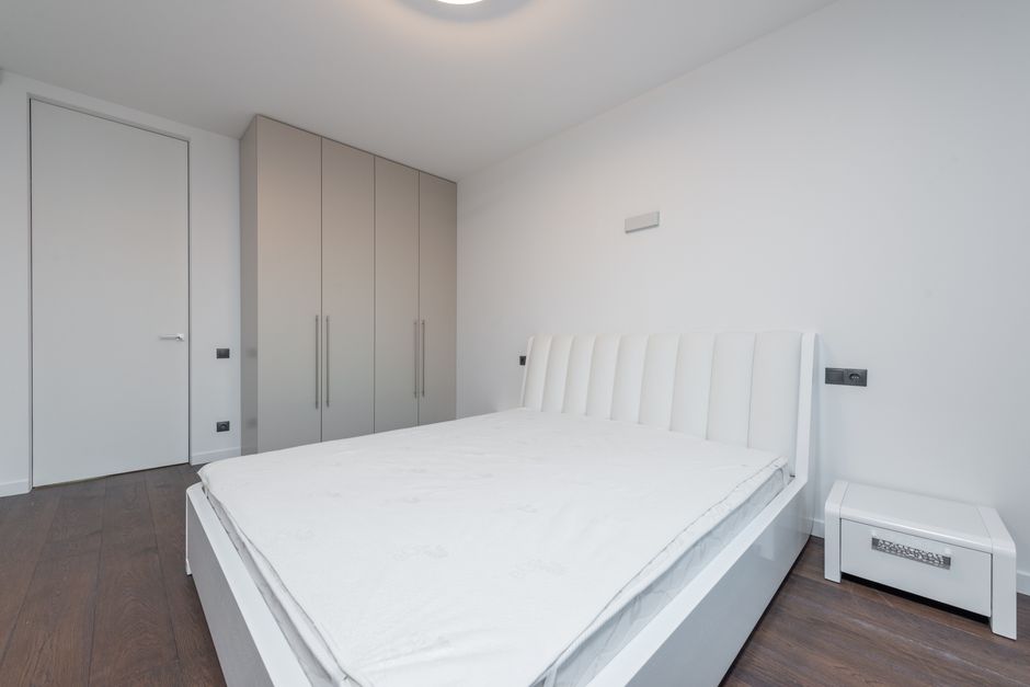 A plain mattress on a bed in a bright bedroom
