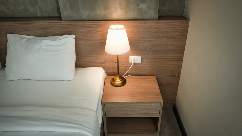 Portable white noise machine with soft night light by a bed