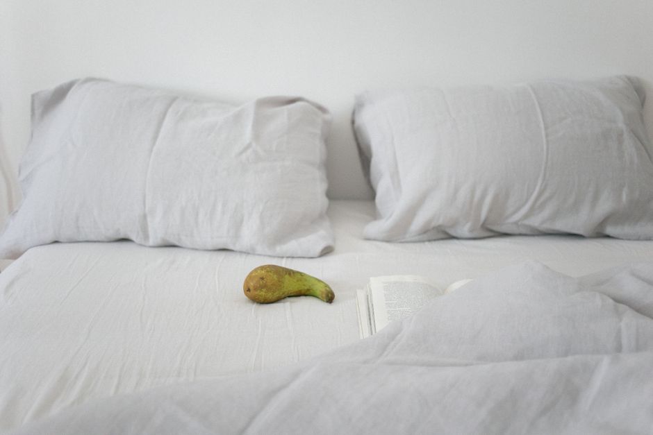 Two pale linen pillows on a rumpled bed with an open book